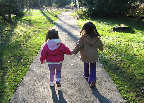 Two girls walking holding hands