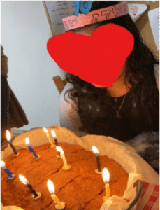 Girl with face covered by heart emoji blowing our candles on a cake